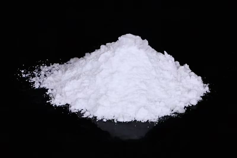 Anhydrous magnesium sulfate: white powder heaped on a dark background